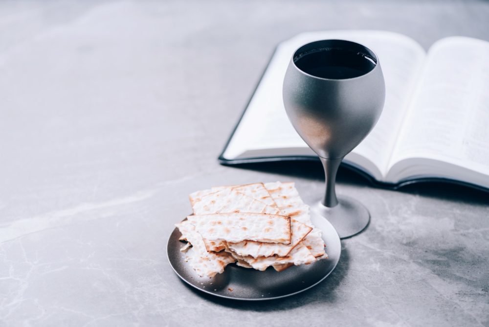 Unleavened bread, chalice of wine, Holy Bible on grey background. Christian communion for reminder